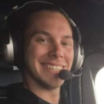 A portrait of Antoine Forest, a 30-year-old Air Canada Express pilot, smiling in the cockpit of an airplane while wearing a headset.